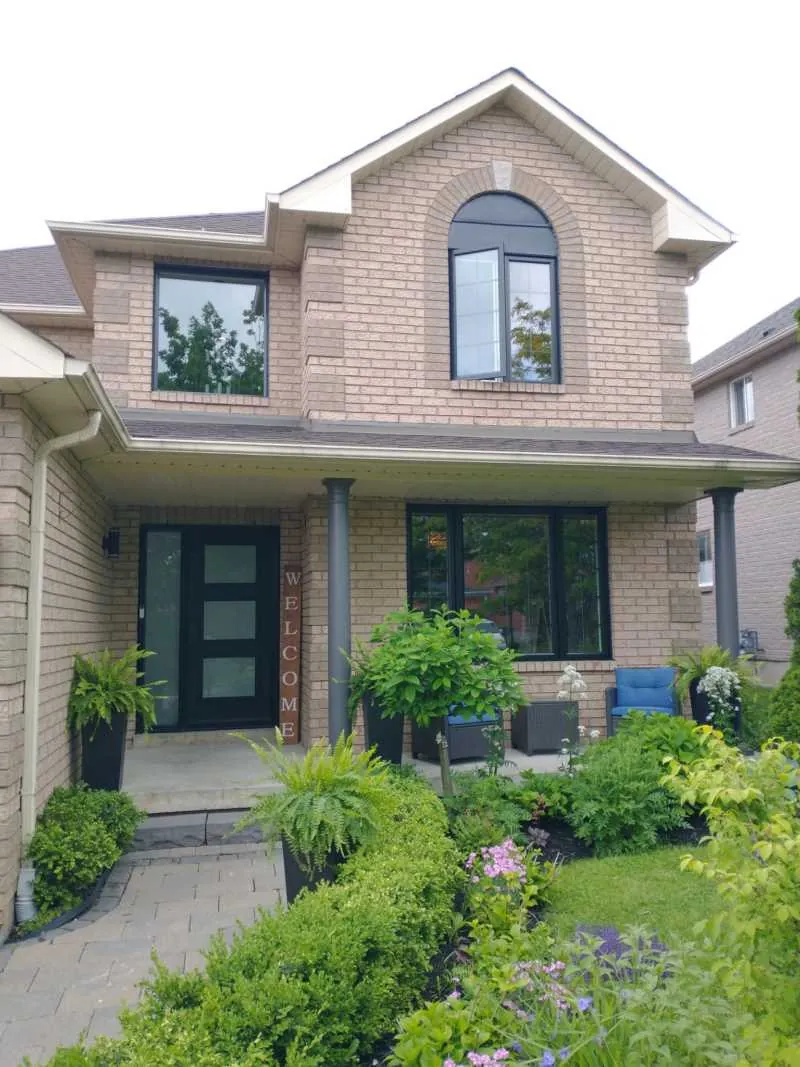 Two-storey brick home with black windows, an arched window and a modern black front door, installed by Panorama Windows & Doors Two-storey brick home with black windows, an arched window and a modern black front door