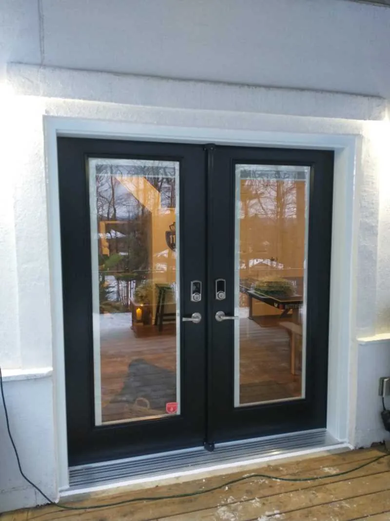 Black French doors with decorative glass on stucco