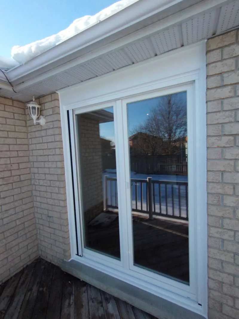 White patio door on a brick wall off a deck