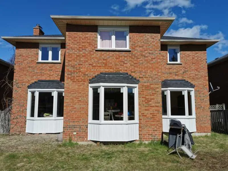 Three new bay windows on the back of a brick home
