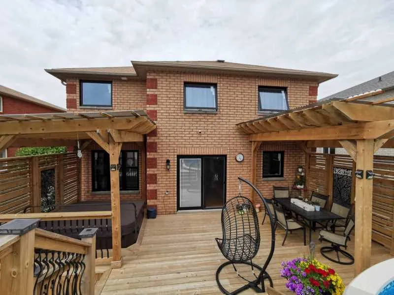 New black windows and patio door on a brick home with a pergola deck