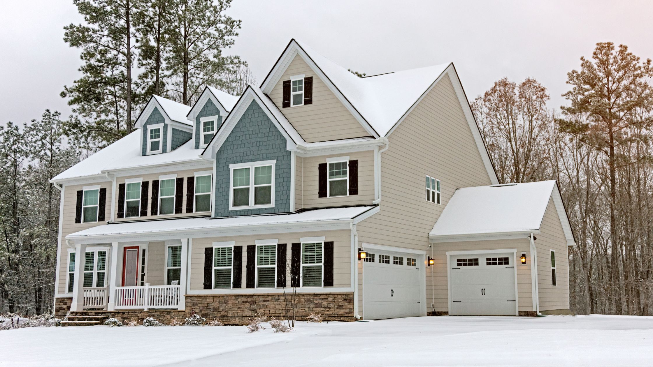 Modern home in winter with snow-covered roof and visible triple-pane windows, showcasing the benefits of triple pane windows in cold climates.