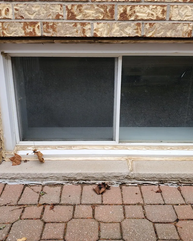 Basement Slider Window Replaced: before Basement window above a paved patio before replacement