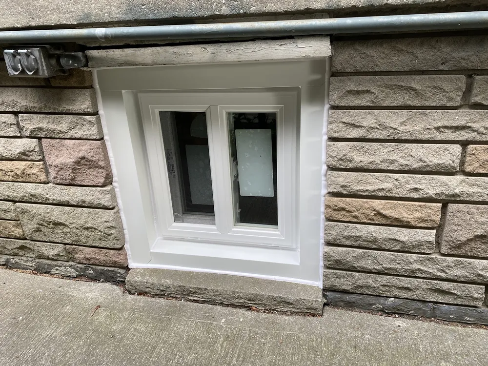 Basement slider window on a stone wall