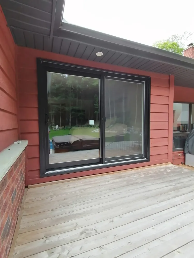 Black sliding patio door on red siding