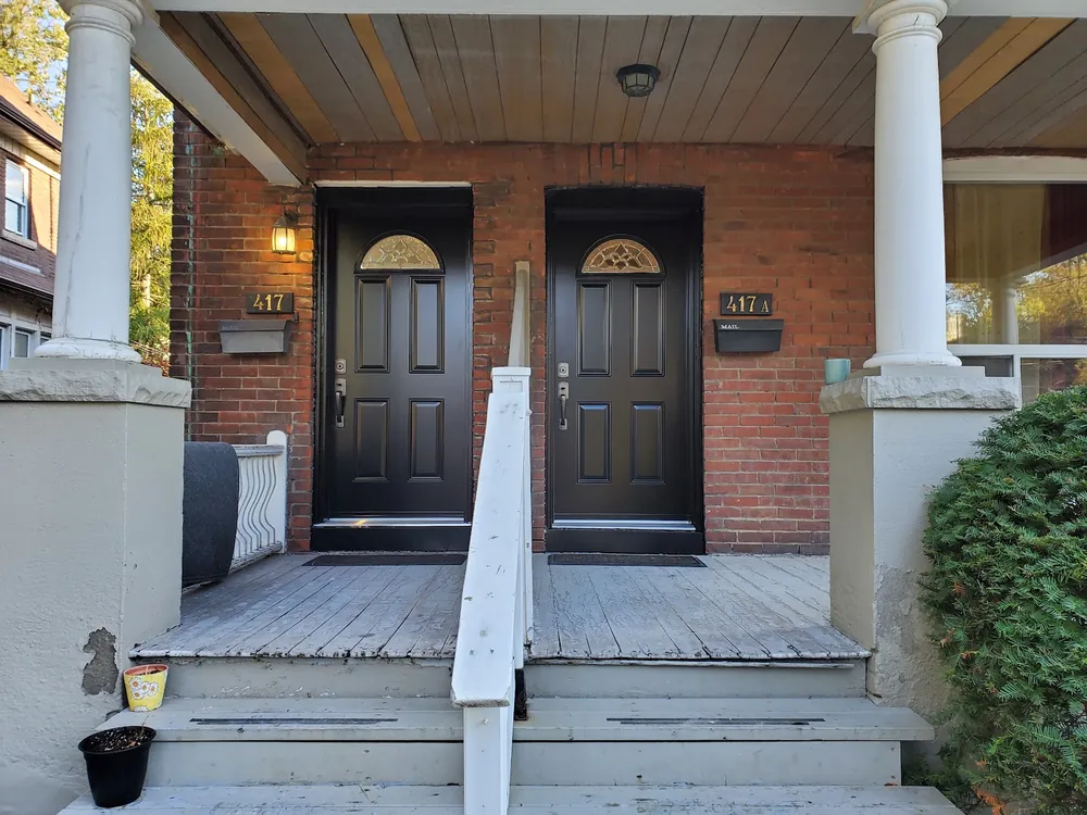 Two black steel entry doors on a porch