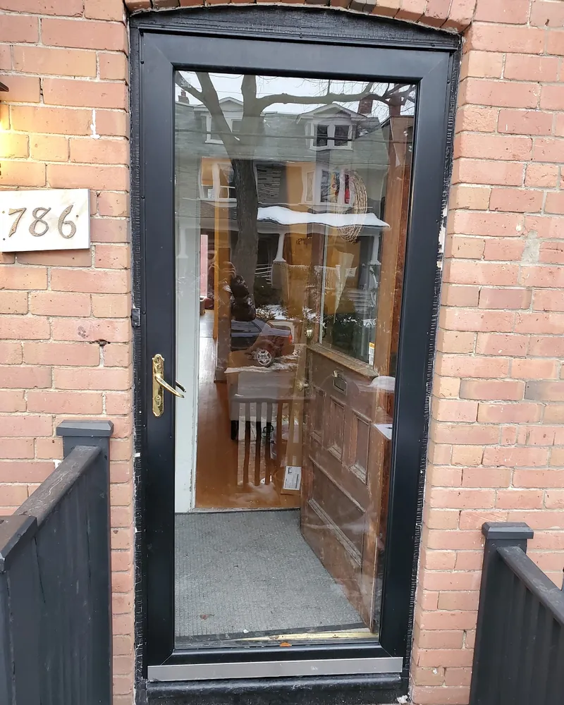 Storm Door Swapped for a Black Steel Door: before Front door on a brick porch with railings before replacement