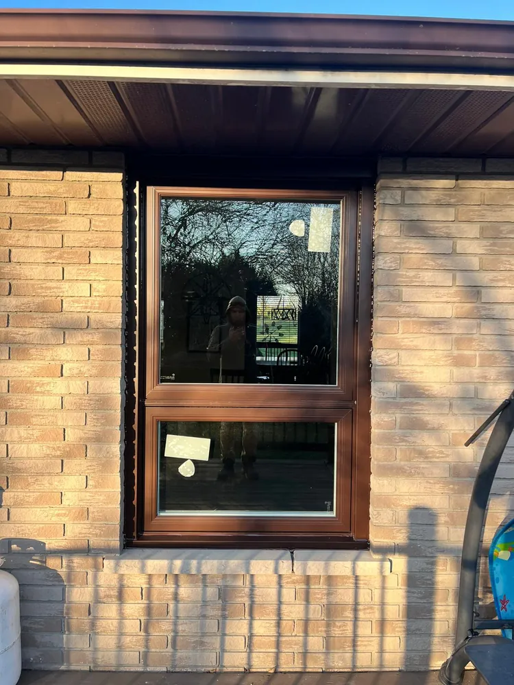Brown awning window under a fixed window on a brick home