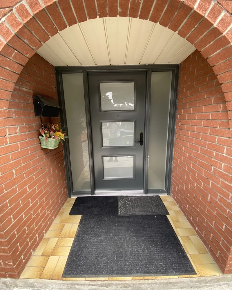 Ornate Entry Door to Modern Grey Door: after Entry door with two sidelights under a brick arch after replacement