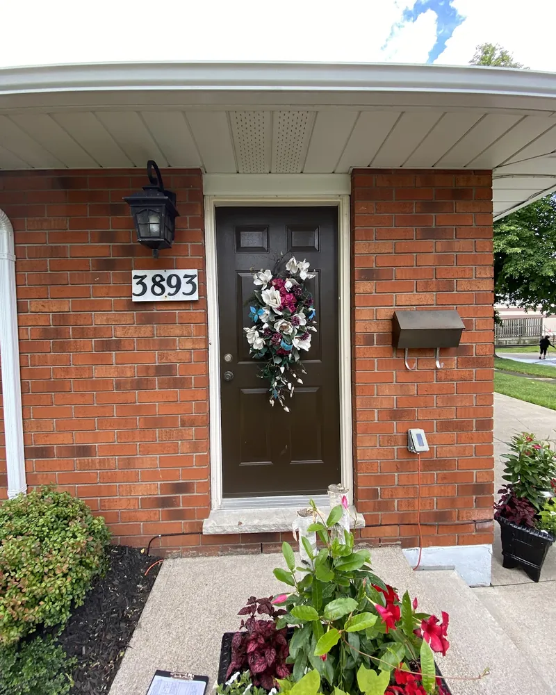 Front door on a red brick porch before replacement