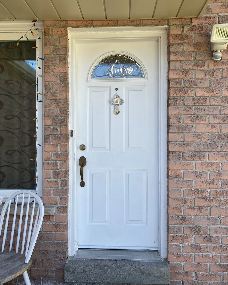 White front door on a brick porch before replacement