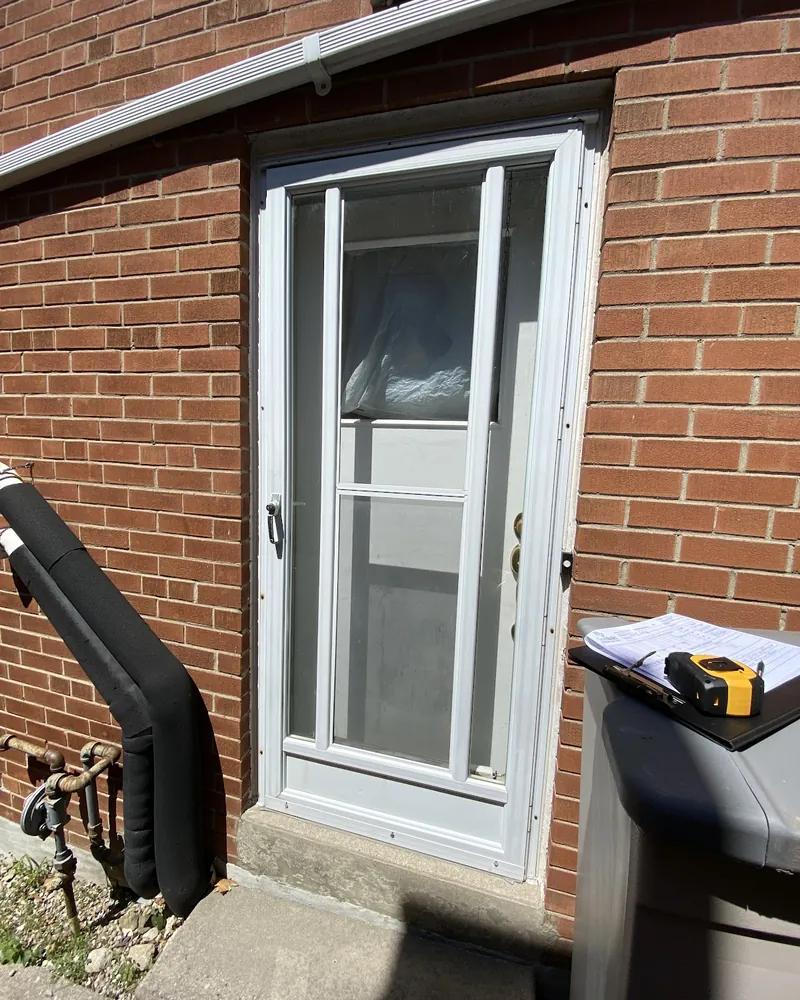 Side Door and Storm Door Replaced: before Side entrance door on a brick wall before replacement