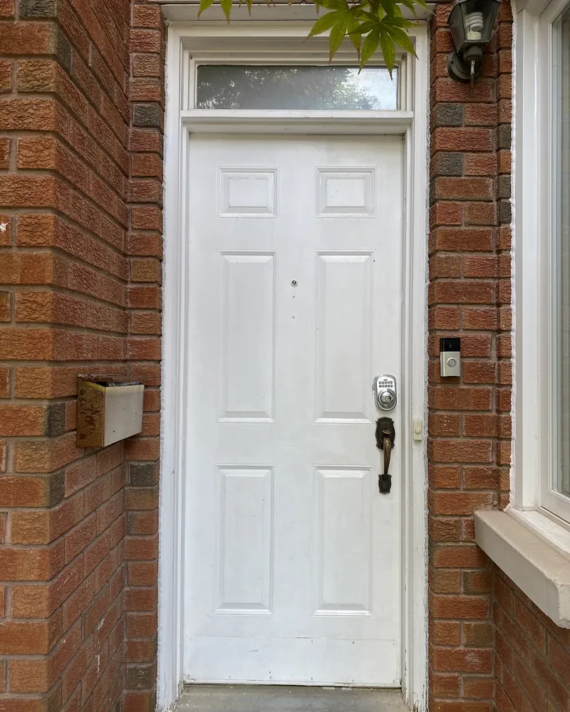 Front door with a transom on a brick wall before replacement