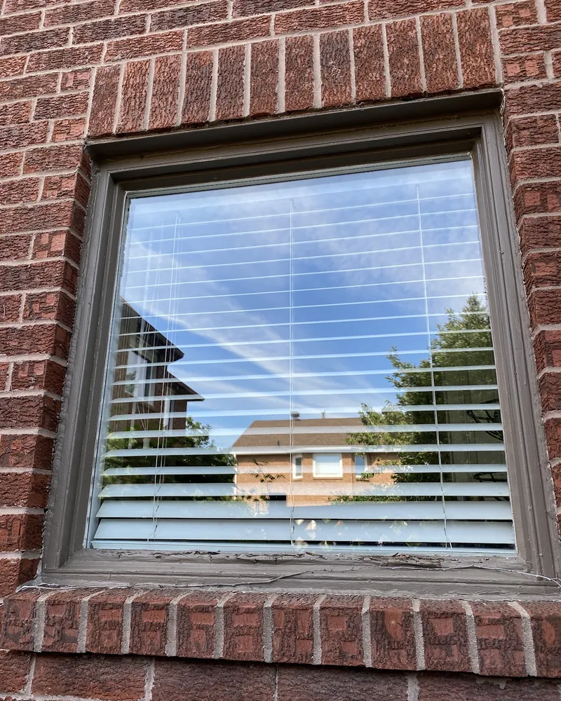 Brown Frame Window to White Vinyl: before Large window on a brick wall before replacement in Brampton